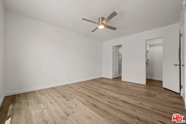 a view of empty room with wooden floor and ceiling fan