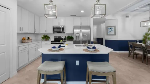 a kitchen with stainless steel appliances a sink a stove a table and chairs