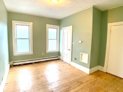 a view of an empty room with window and a kitchen