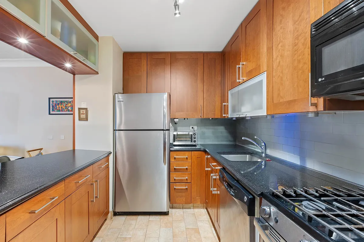 510 East 80th Street, Unit 4D Manhattan, NY 10075 - Photo 3 of 20 a kitchen with stainless steel appliances granite countertop a refrigerator a stove and a sink with wooden floor