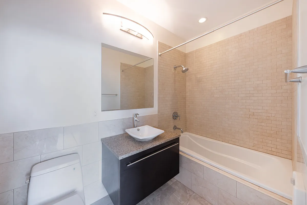 51-42 27th Street, Unit 6C Queens, NY 11101 - Photo 8 of 10 a bathroom with a sink a toilet and shower