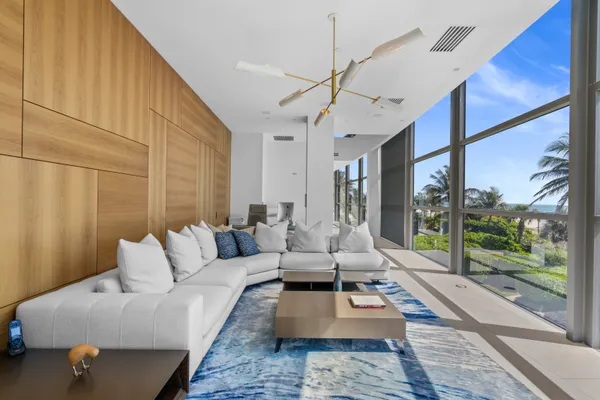 a living room with furniture large windows and wooden floor