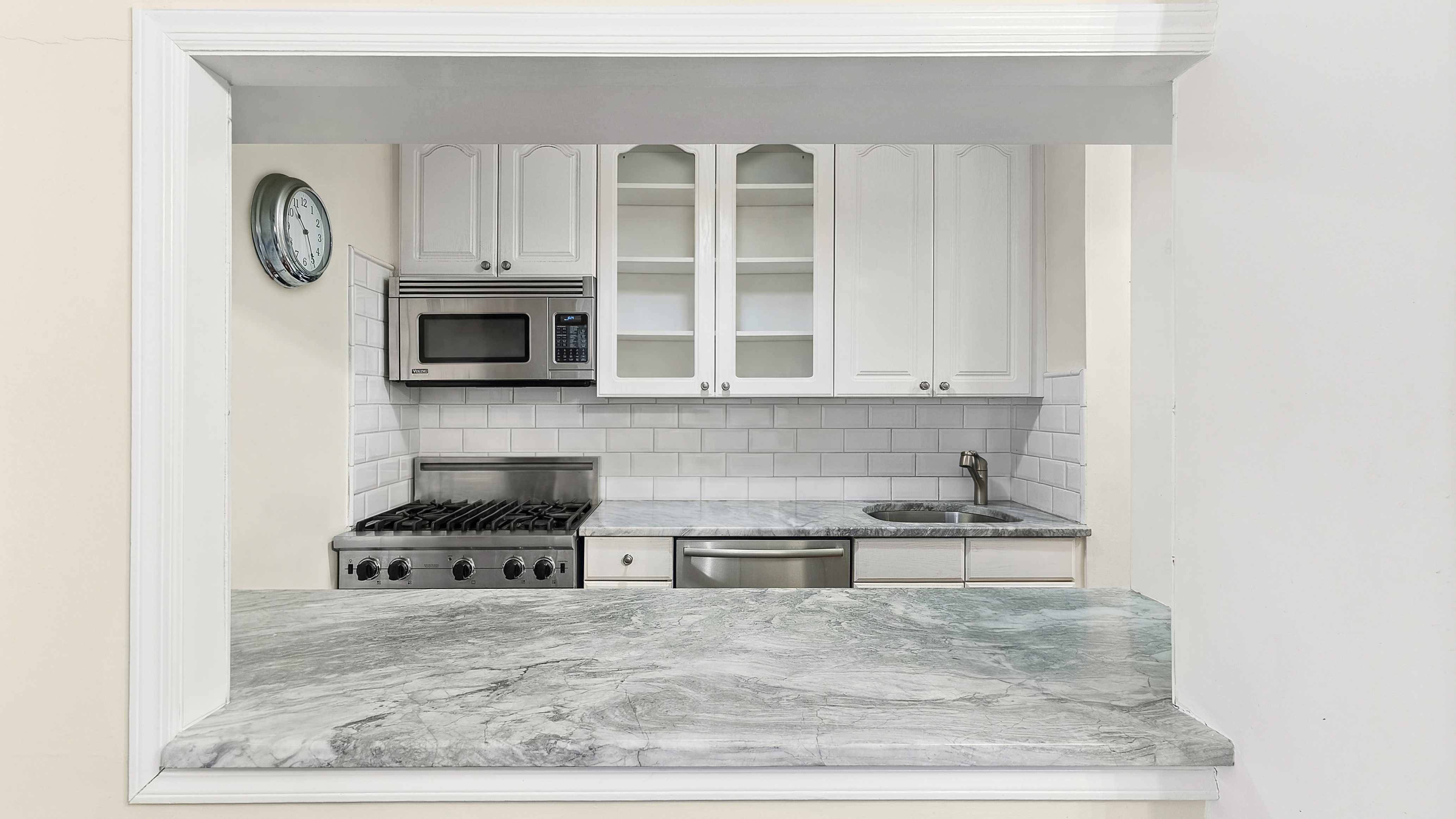 333 East 79th Street, Unit 8X Manhattan, NY 10075 - Photo 3 of 8 a kitchen with stainless steel appliances granite countertop a stove a microwave and white cabinets