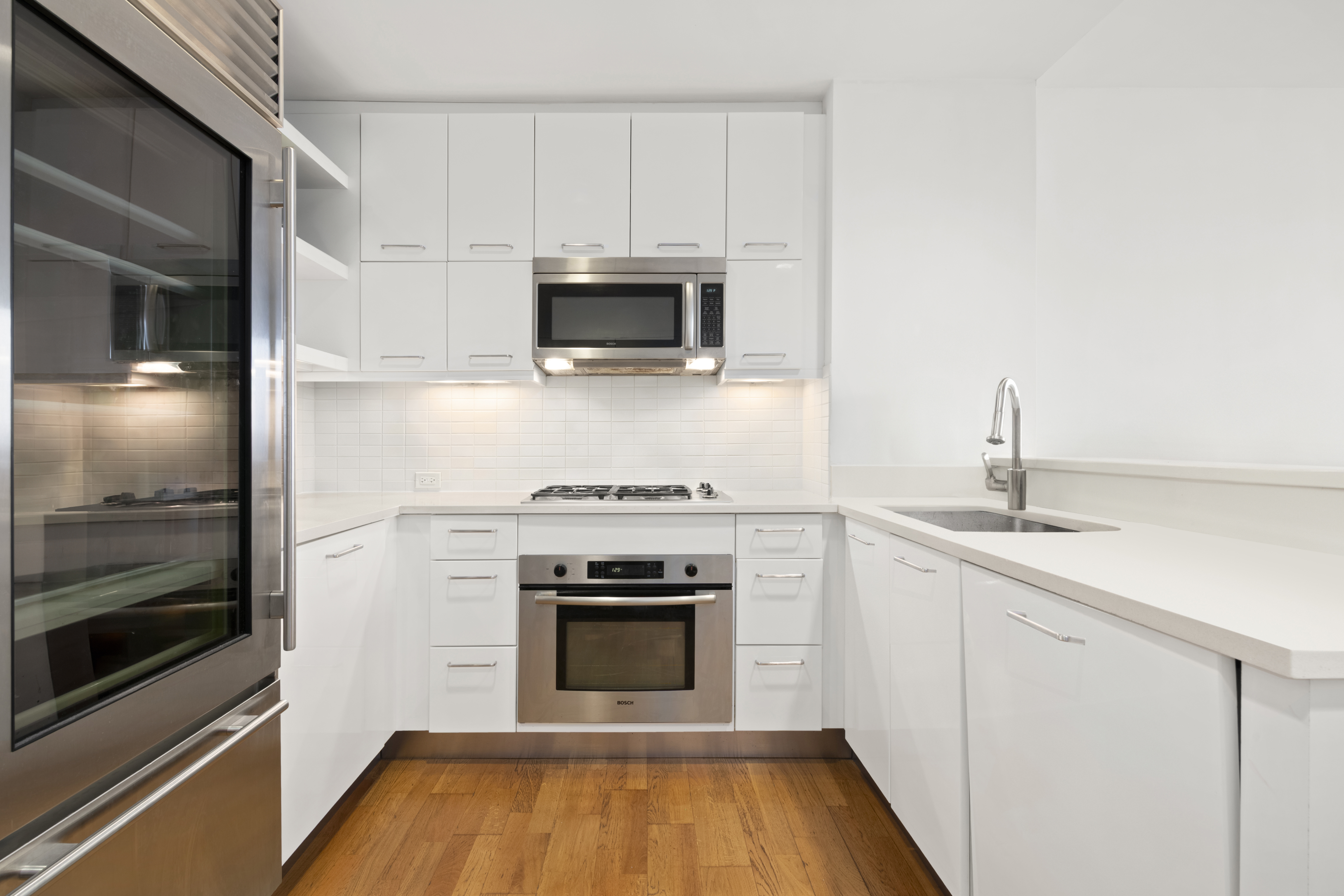 635 West 42nd Street, Unit 12D Manhattan, NY 10036 - Photo 7 of 18 a kitchen with wooden floor and stainless steel appliances