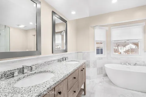 a bathroom with a granite countertop sink and a large mirror