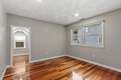 a view of empty room with window and wooden floor