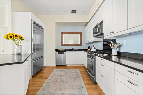 a large kitchen with stainless steel appliances granite countertop a sink and dishwasher a stove top oven with wooden floor