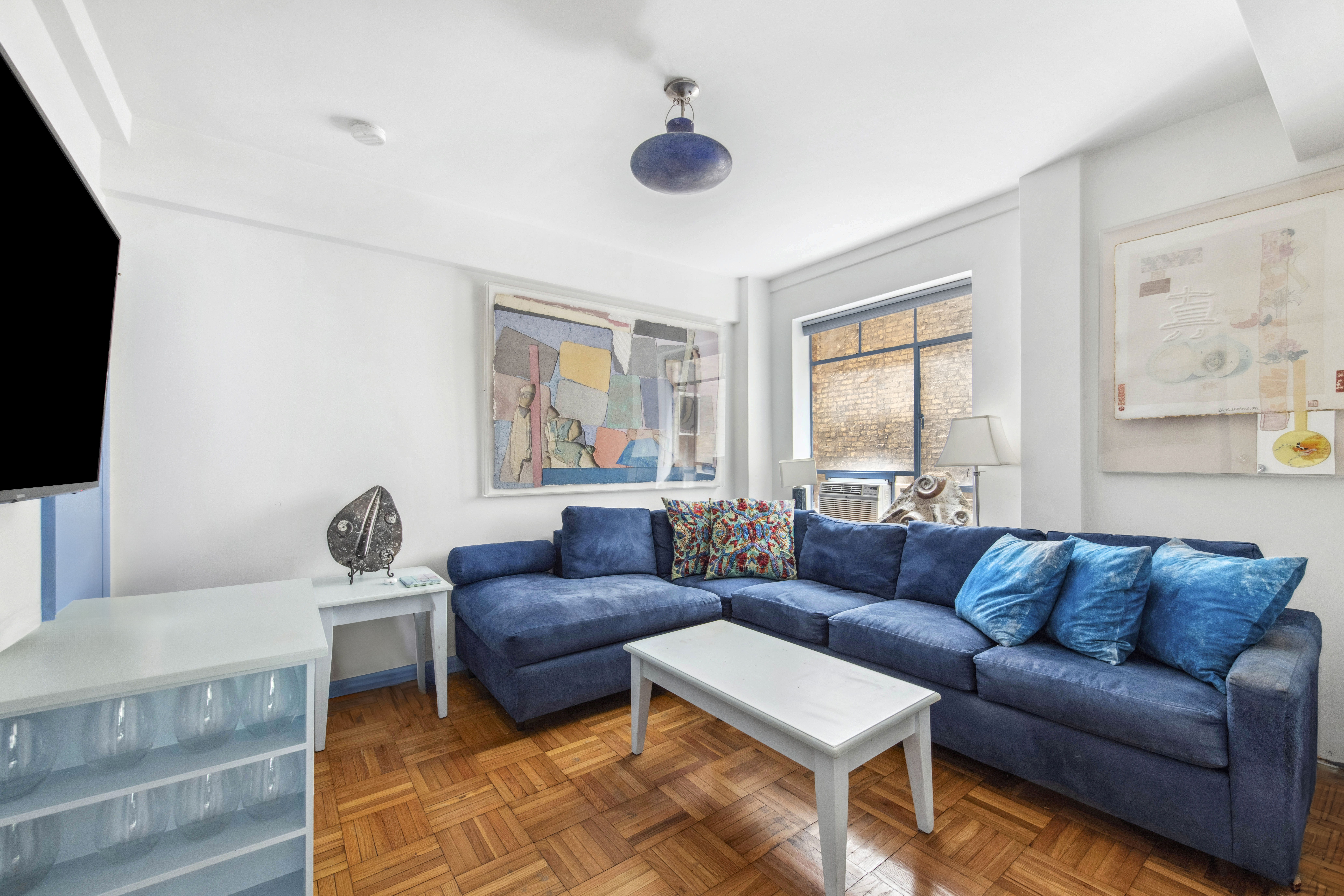 45 West 54th Street, Unit 3CD Manhattan, NY 10019 - Photo 7 of 14 a living room with furniture a flat screen tv and a window