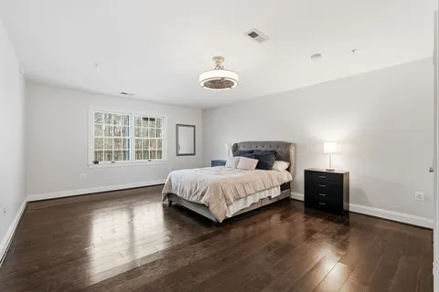 a spacious bedroom with a bed and wooden floor