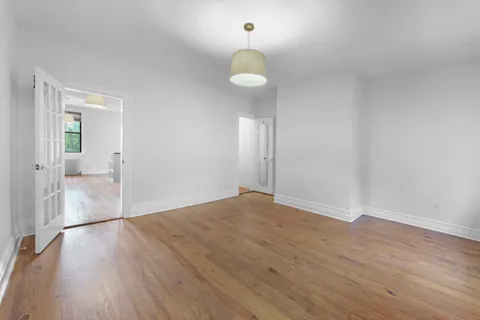 a view of an empty room with wooden floor and a large window