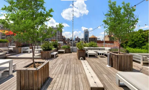 a view of a balcony with chairs potted plants and a large tree