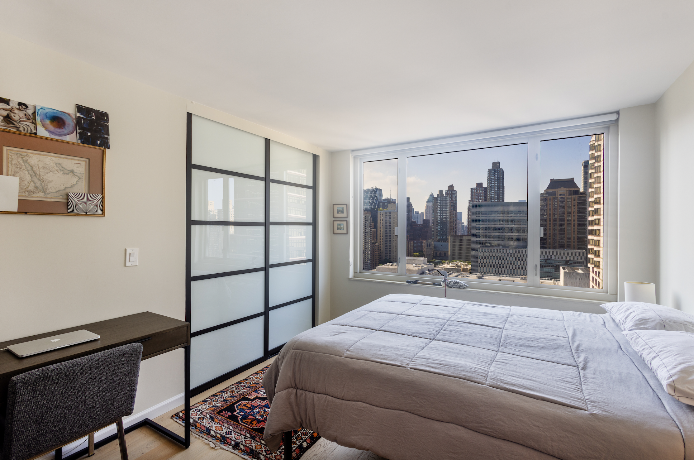 130 West 67th Street, Unit 26D Manhattan, NY 10023 - Photo 4 of 9 a bedroom with a bed a window and a flat screen tv