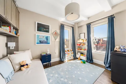 a living room with furniture a flat screen tv and a refrigerator