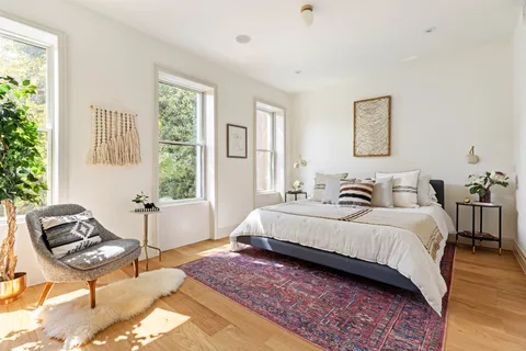 a spacious bedroom with a bed and wooden floor