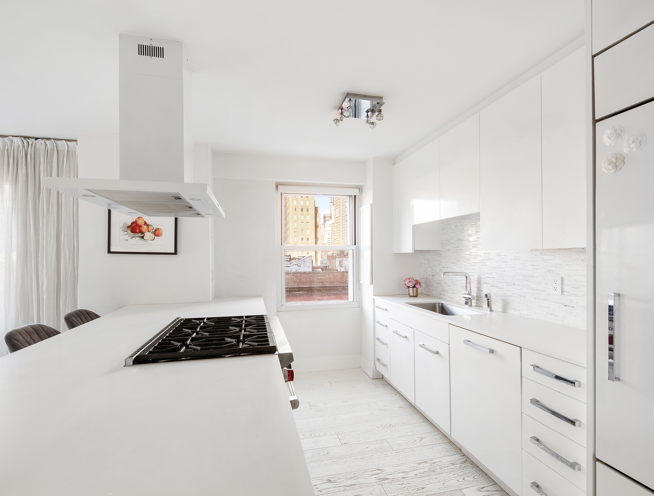 150 East 61st Street, Unit 7E Manhattan, NY 10065 - Photo 5 of 12 a kitchen with a sink a stove and white cabinets