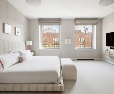 a bedroom with a bed and a flat tv screen on a dresser
