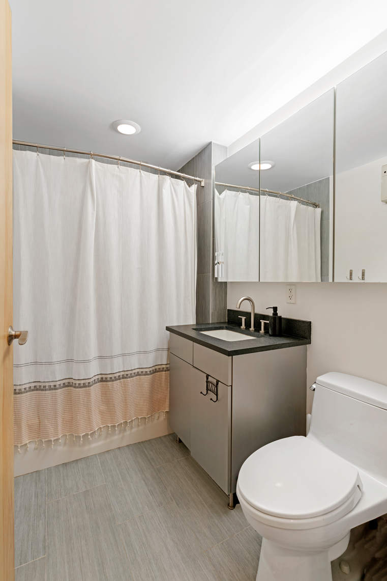 1595 Lexington Avenue, Unit 4H Manhattan, NY 10029 - Photo 7 of 9 a bathroom with a sink a toilet and shower
