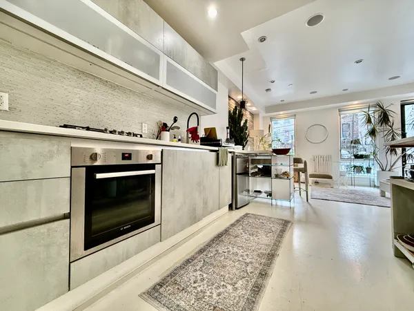 a living room with stainless steel appliances furniture a rug and a fireplace