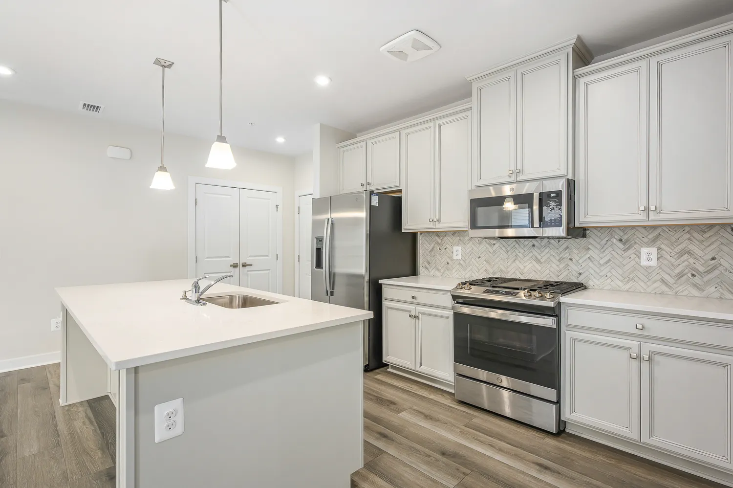 a kitchen with stainless steel appliances granite countertop a sink a stove a refrigerator and island with wooden floor