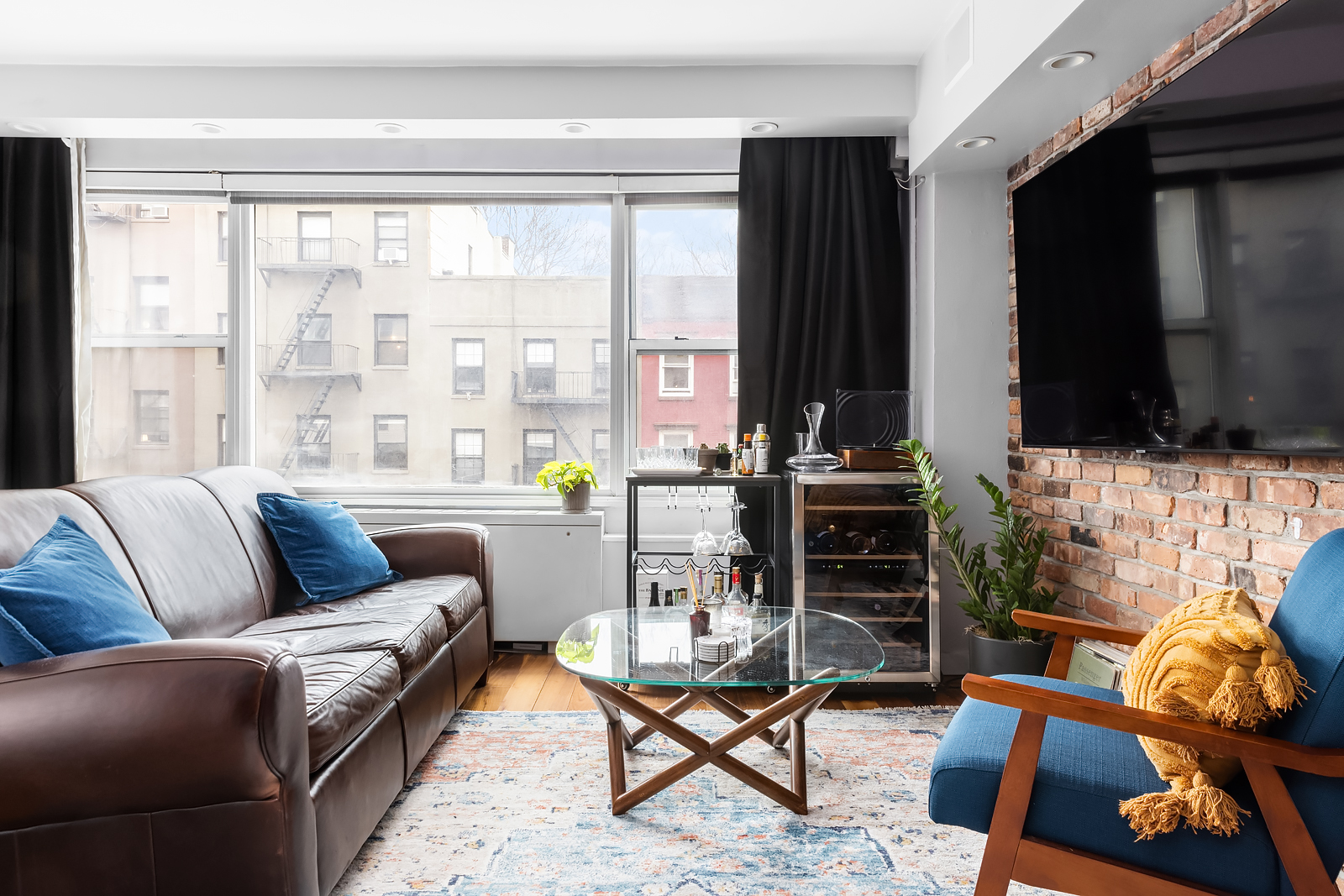 33 Greenwich Avenue, Unit 4E Manhattan, NY 10014 - Photo 2 of 10 a living room with furniture a flat screen tv and a floor to ceiling window