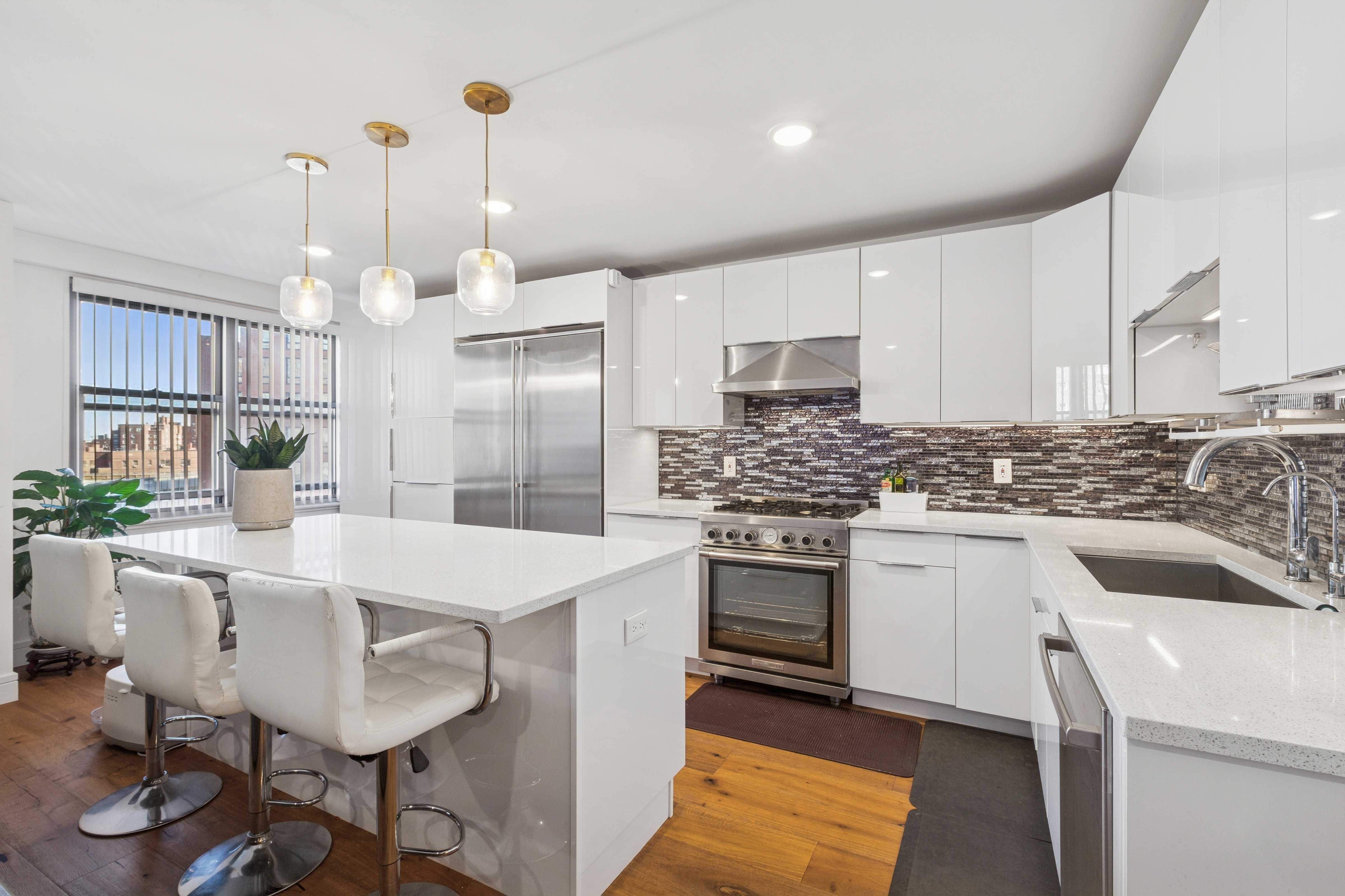 70-25 Yellowstone Boulevard, Unit 8N Queens, NY 11375 - Photo 2 of 19 a kitchen with a white center island a sink cabinets and stainless steel appliances