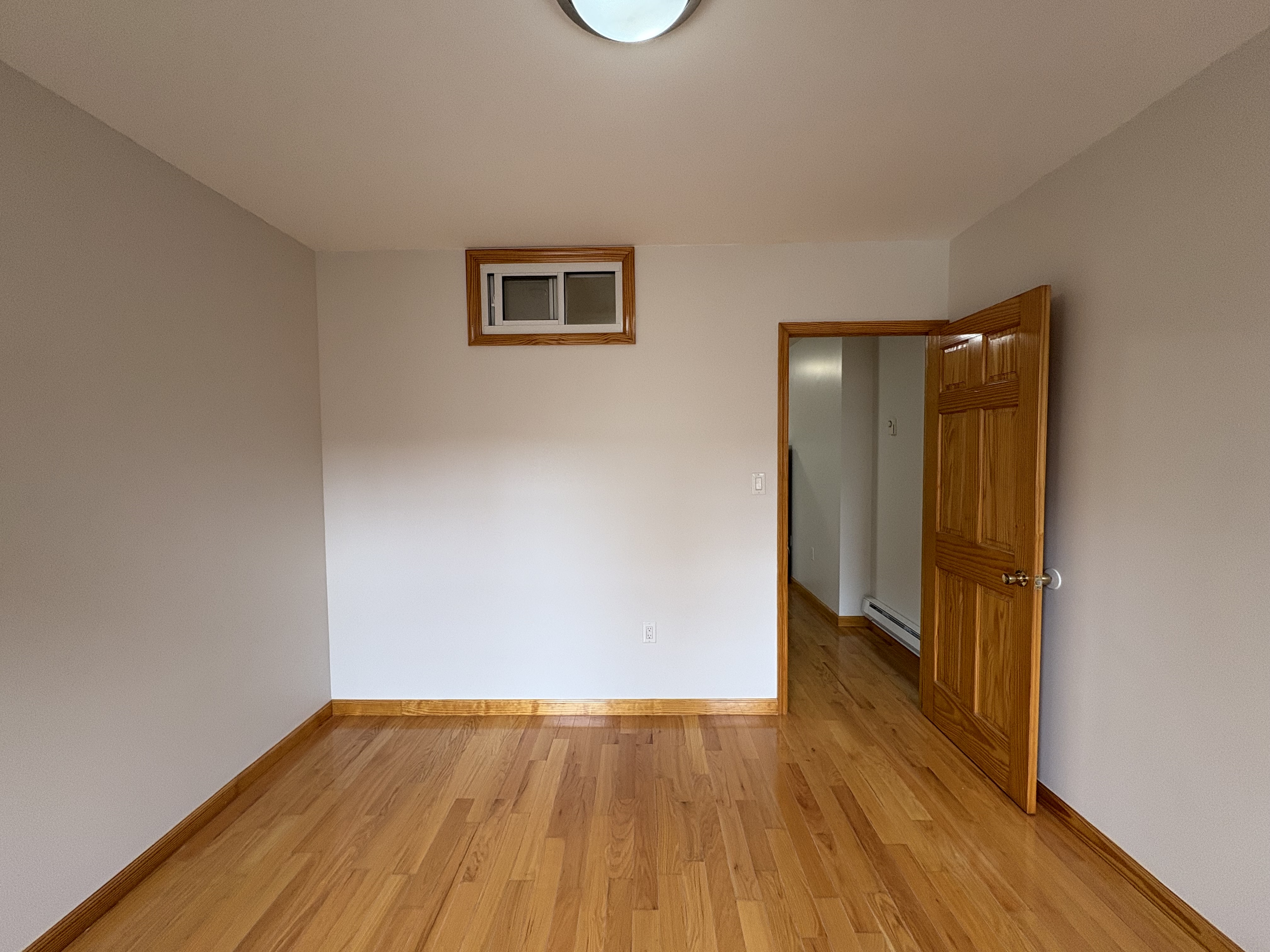 38 Ludlow Street, Unit 15 Manhattan, NY 10002 - Photo 4 of 16 a view of an empty room with wooden floor and a window