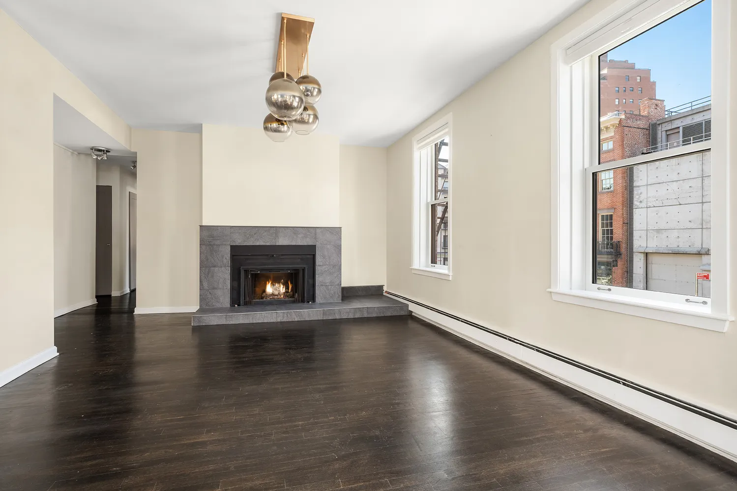 a view of an empty room with wooden floor fireplace and a window