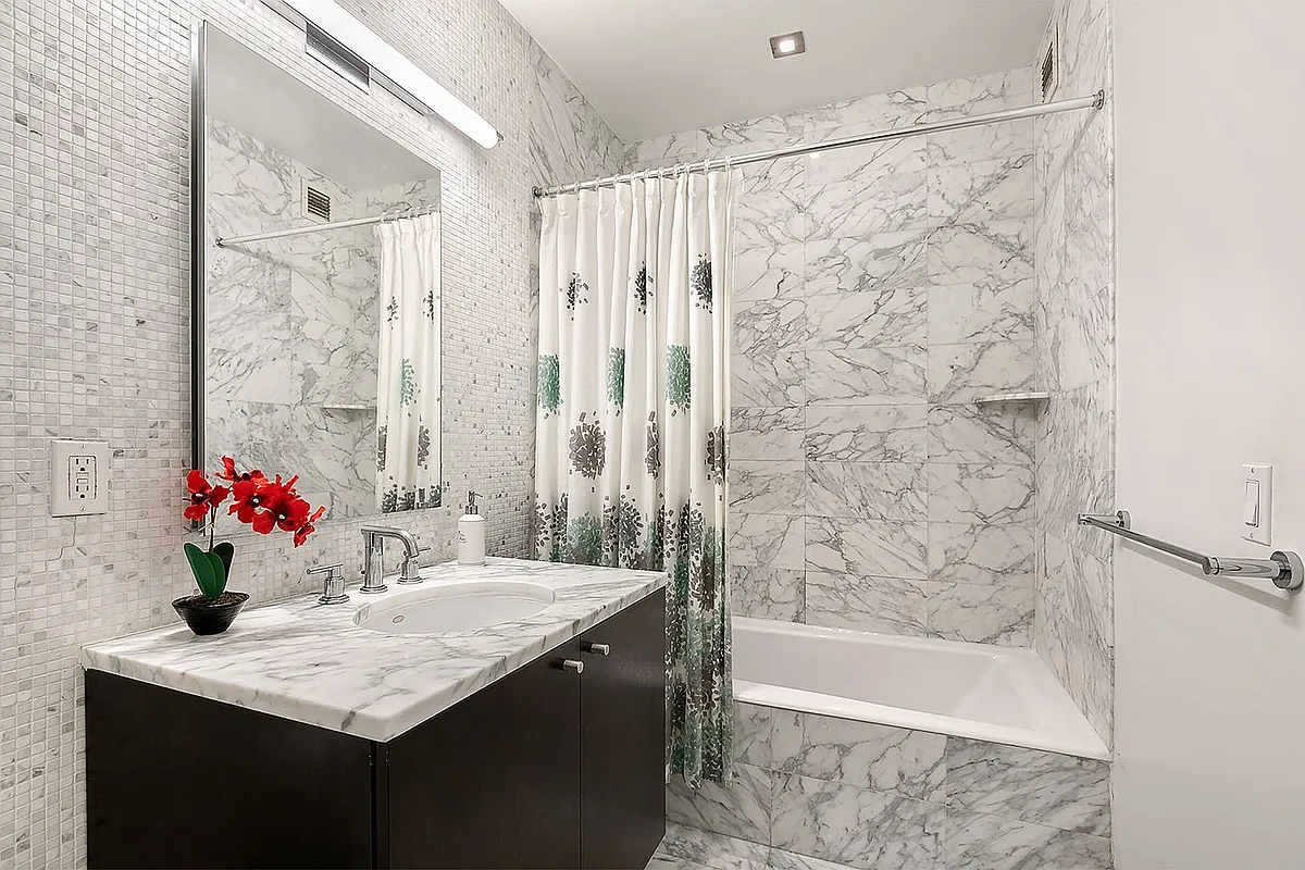 46-30 Center Boulevard, Unit 406 Queens, NY 11109 - Photo 7 of 23 a bathroom with a granite countertop sink a bathtub and a shower