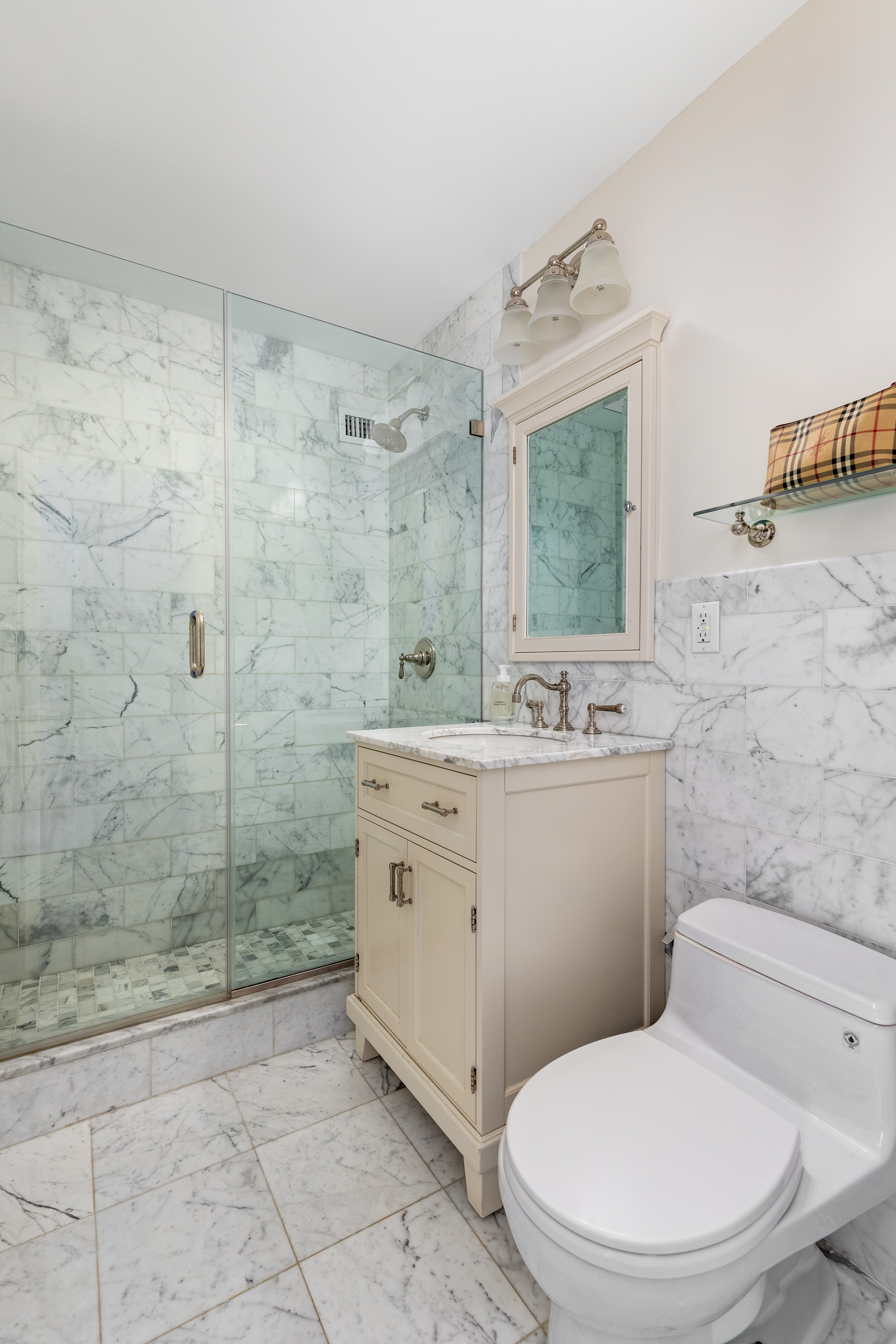 575 Main Street, Unit 1312 Manhattan, NY 10044 - Photo 13 of 25 a bathroom with a granite countertop toilet a sink a mirror and shower