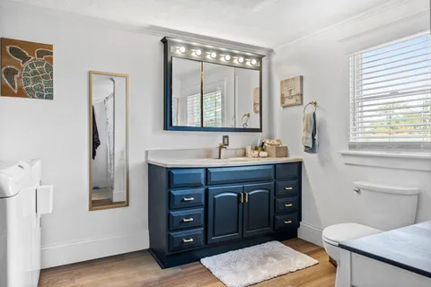 a bathroom with a granite countertop sink toilet a mirror and window