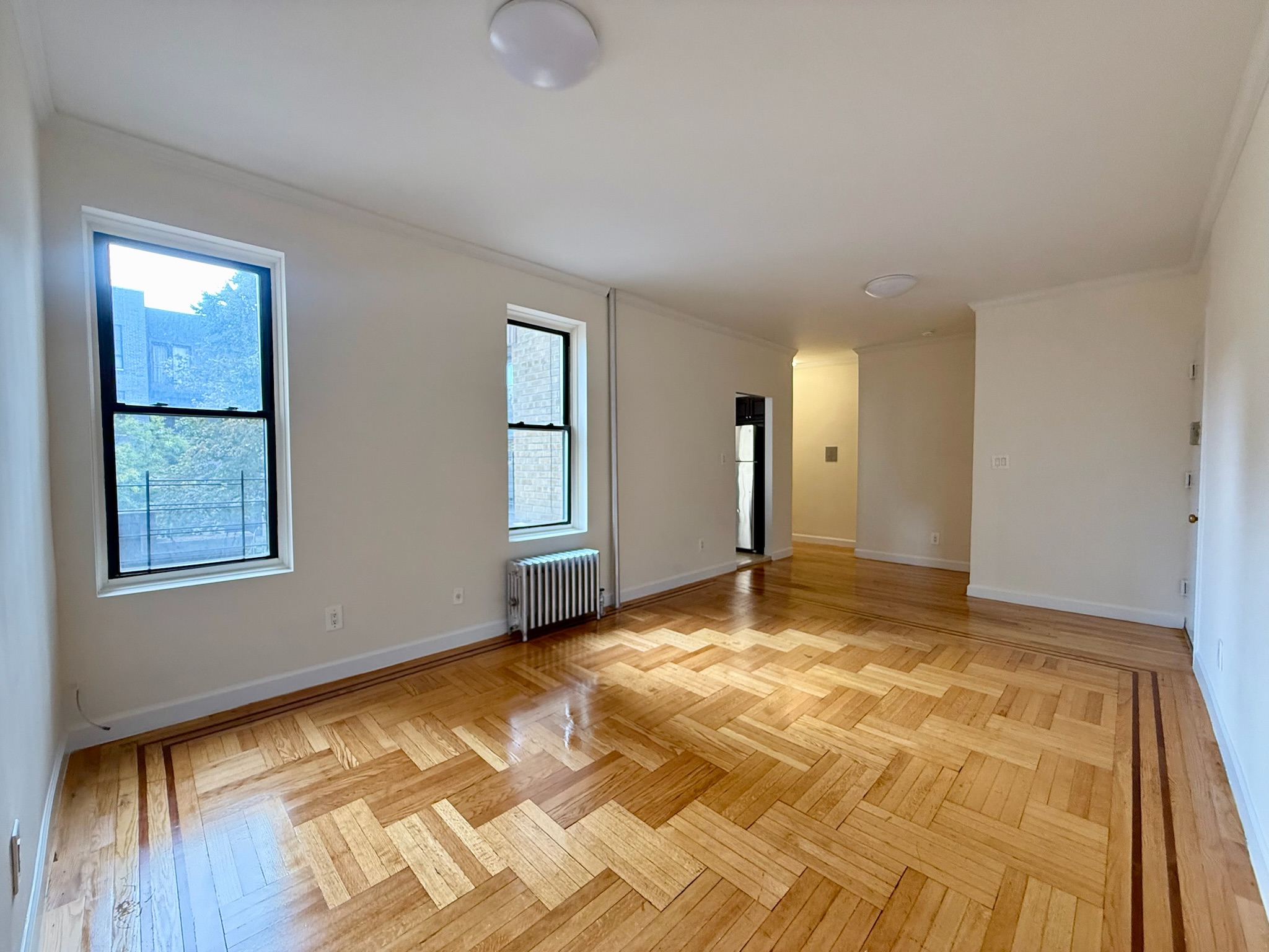 957 Greene Avenue, Unit BWEST Brooklyn, NY 11221 - Photo 3 of 8 a view of an empty room with window and wooden floor