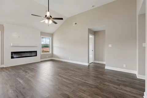 an empty room with wooden floor chandelier and windows