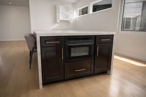 a utility room with stainless steel appliances wooden cabinets and wooden floor