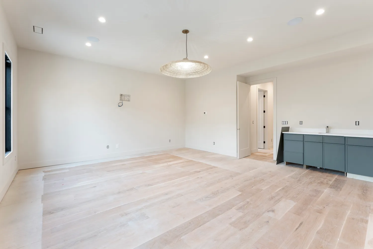a view of a hallway with wooden floor and a bathroom