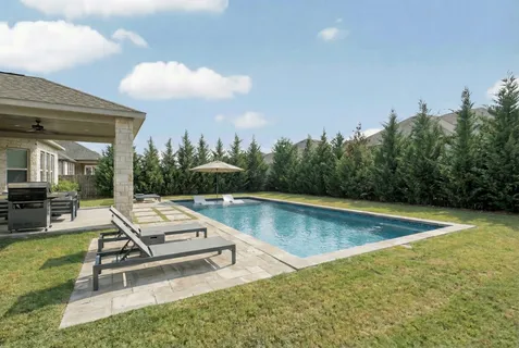 a view of a swimming pool with lounge chair in front of house