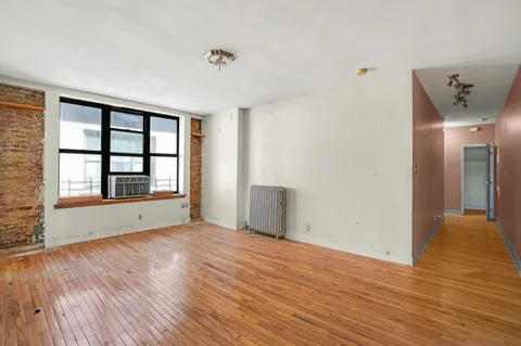 a view of an empty room with window and wooden floor