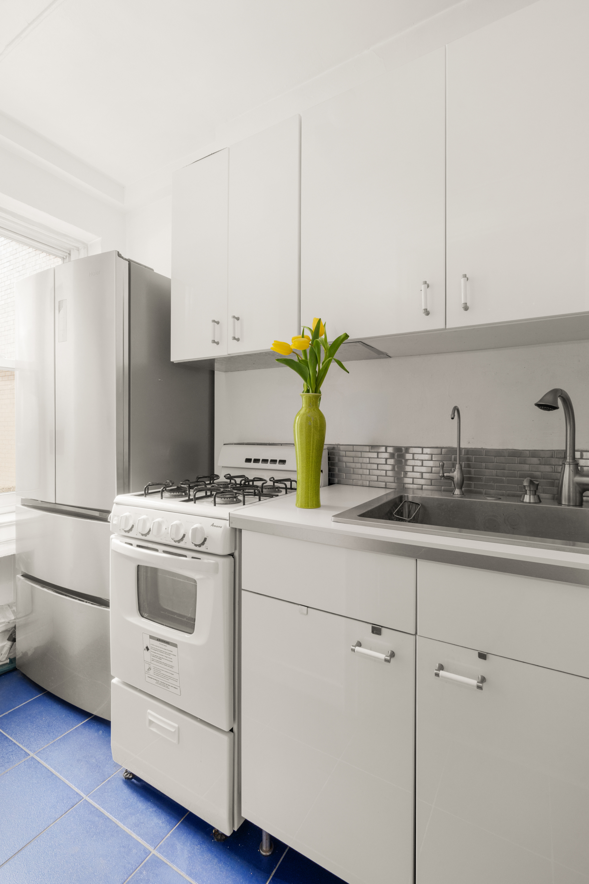 227 East 57th Street, Unit 3DEF Manhattan, NY 10022 - Photo 11 of 13 a kitchen with stainless steel appliances white cabinets and a refrigerator