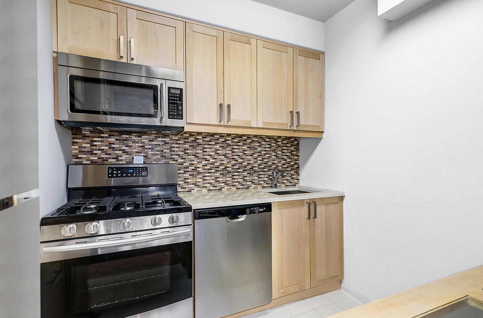 117 East 57th Street, Unit 48G Manhattan, NY 10022 - Photo 4 of 13 a kitchen with stainless steel appliances a stove and a microwave