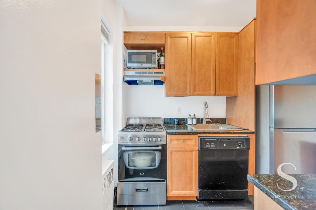 7 Lexington Avenue, Unit 5E Manhattan, NY 10010 - Photo 13 of 27 a kitchen with stainless steel appliances granite countertop a stove a sink and a microwave