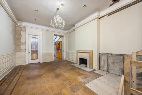 a view of a livingroom with a fireplace a chandelier and windows