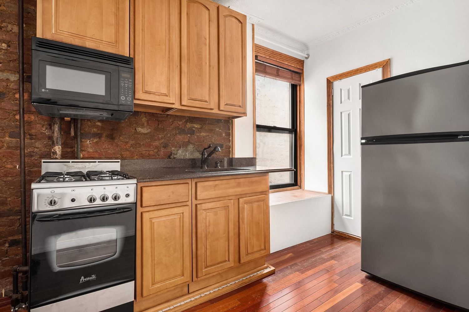 177 Thompson Street, Unit 22 Manhattan, NY 10012 - Photo 4 of 5 a kitchen with granite countertop white cabinets and white appliances