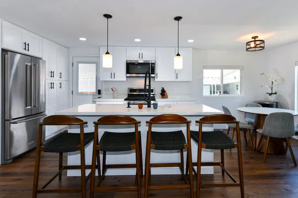 a kitchen with stainless steel appliances a dining table chairs stove and refrigerator