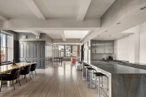 a kitchen with granite countertop a stove a sink a dining table and chairs with wooden floor