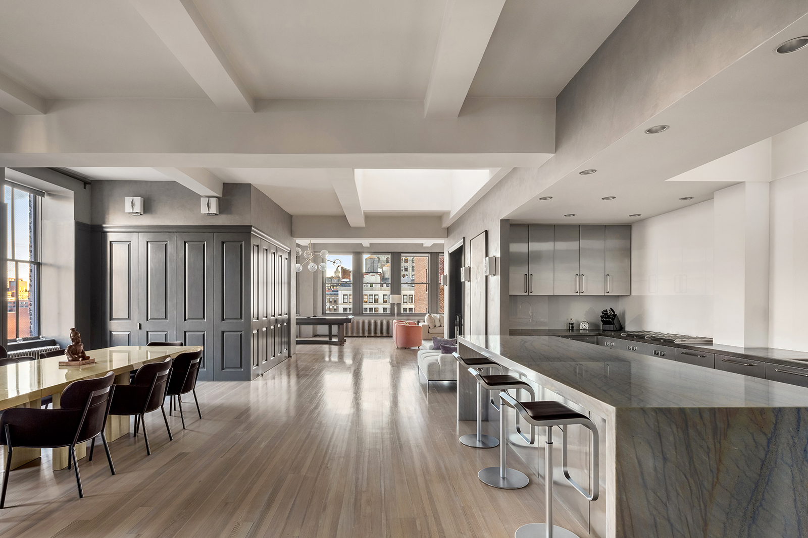 105 East 29th Street, Unit 12PH Manhattan, NY 10016 - Photo 8 of 24 a kitchen with granite countertop a stove a sink a dining table and chairs with wooden floor