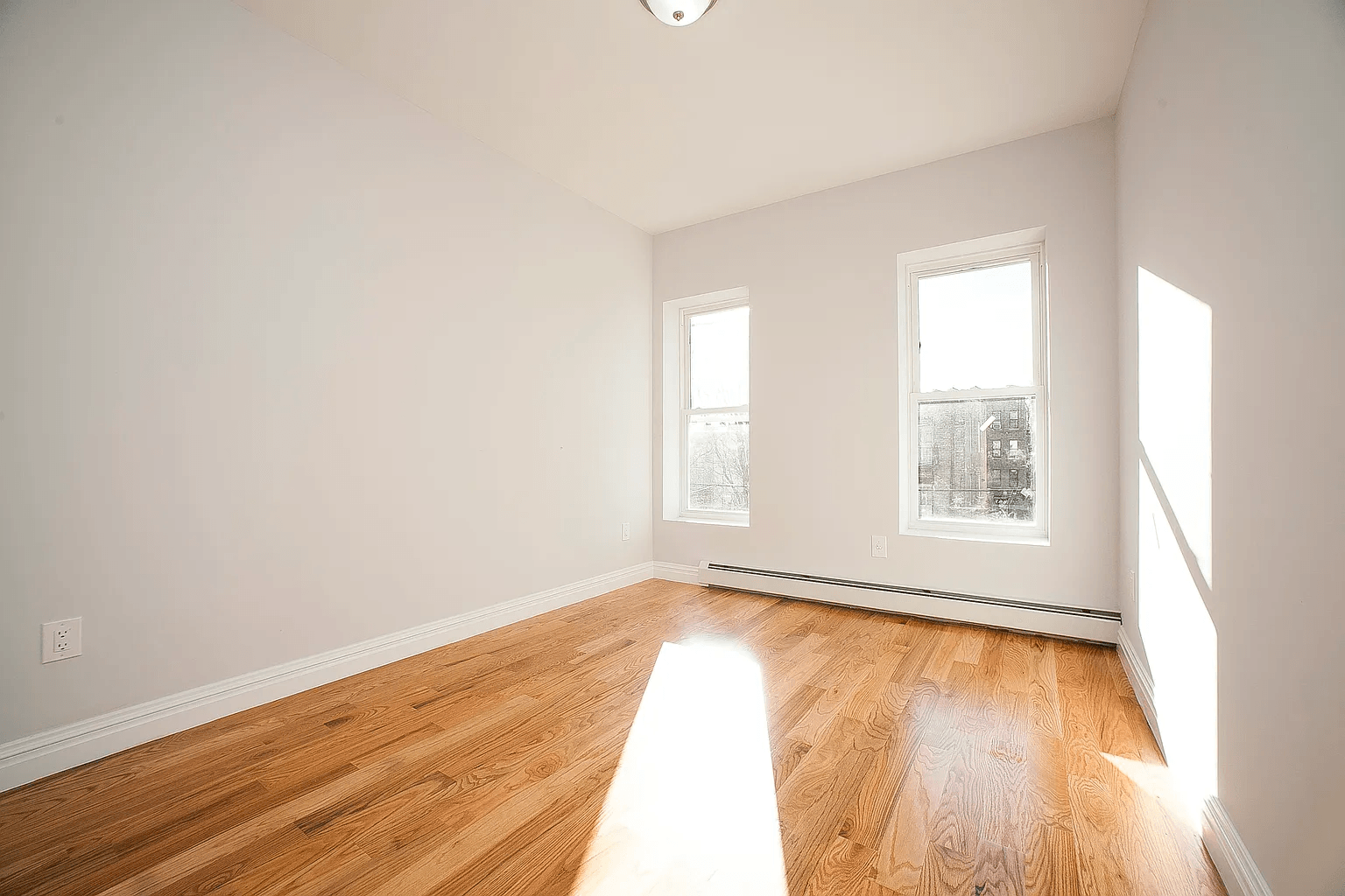 581 Van Siclen Avenue Brooklyn, NY 11207 - Photo 4 of 16 an empty room with wooden floor and windows