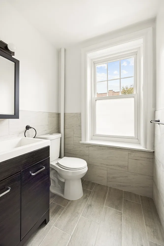a bathroom with a toilet sink vanity and windows