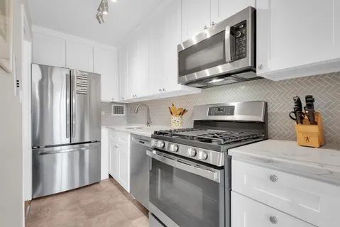 a kitchen with stainless steel appliances granite countertop a stove microwave refrigerator and cabinets