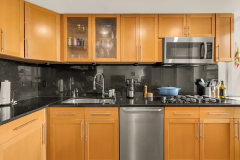 a kitchen with stainless steel appliances granite countertop a stove a sink and a microwave