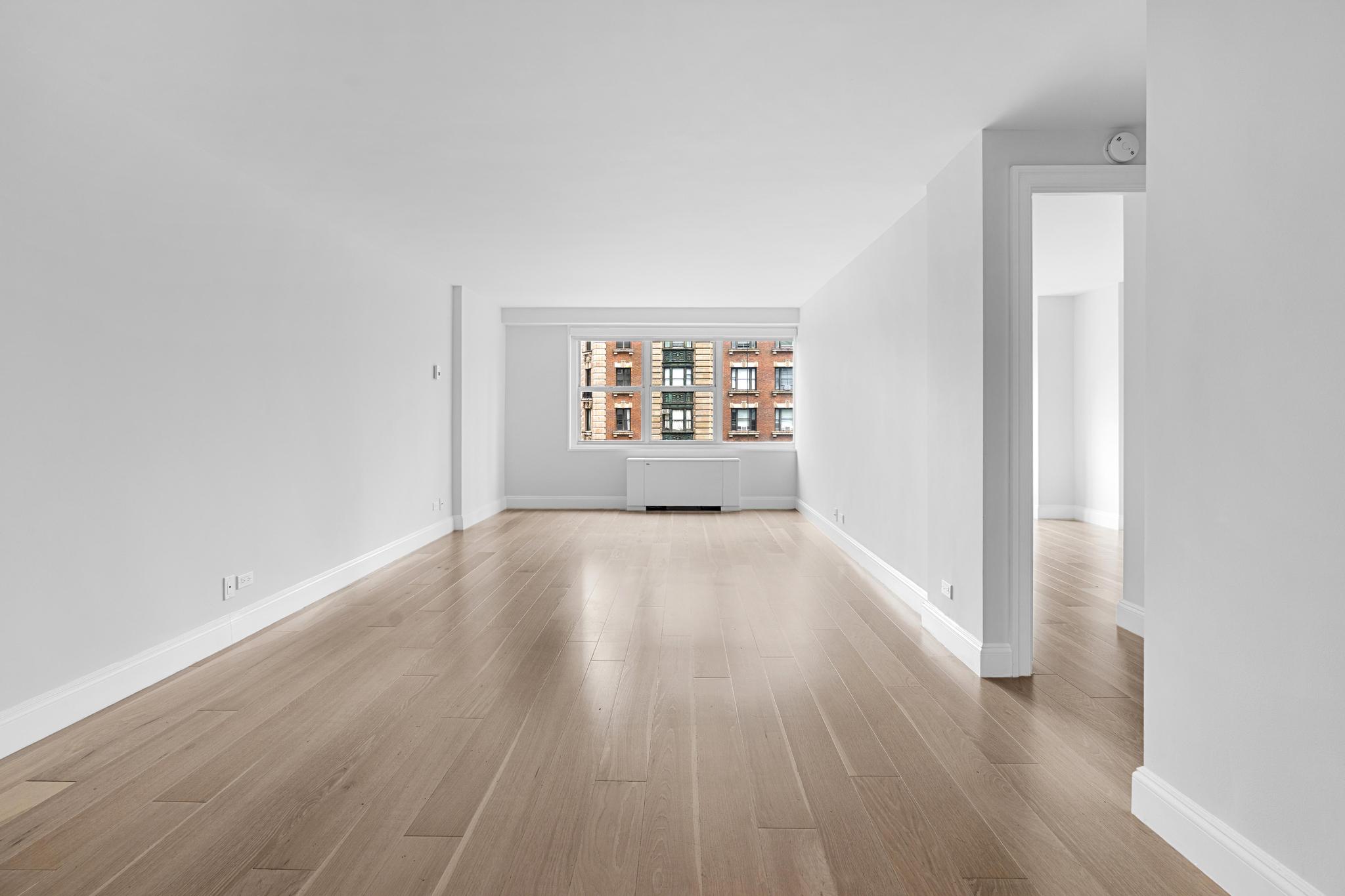 155 West 68th Street, Unit 1027 Manhattan, NY 10023 - Photo 2 of 8 an empty room with wooden floor and windows