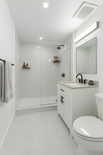 a bathroom with a toilet a sink a mirror and shower